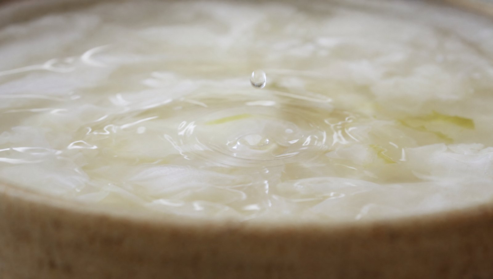 A droplet meeting a brimming ferment surface, the ripple absorbed